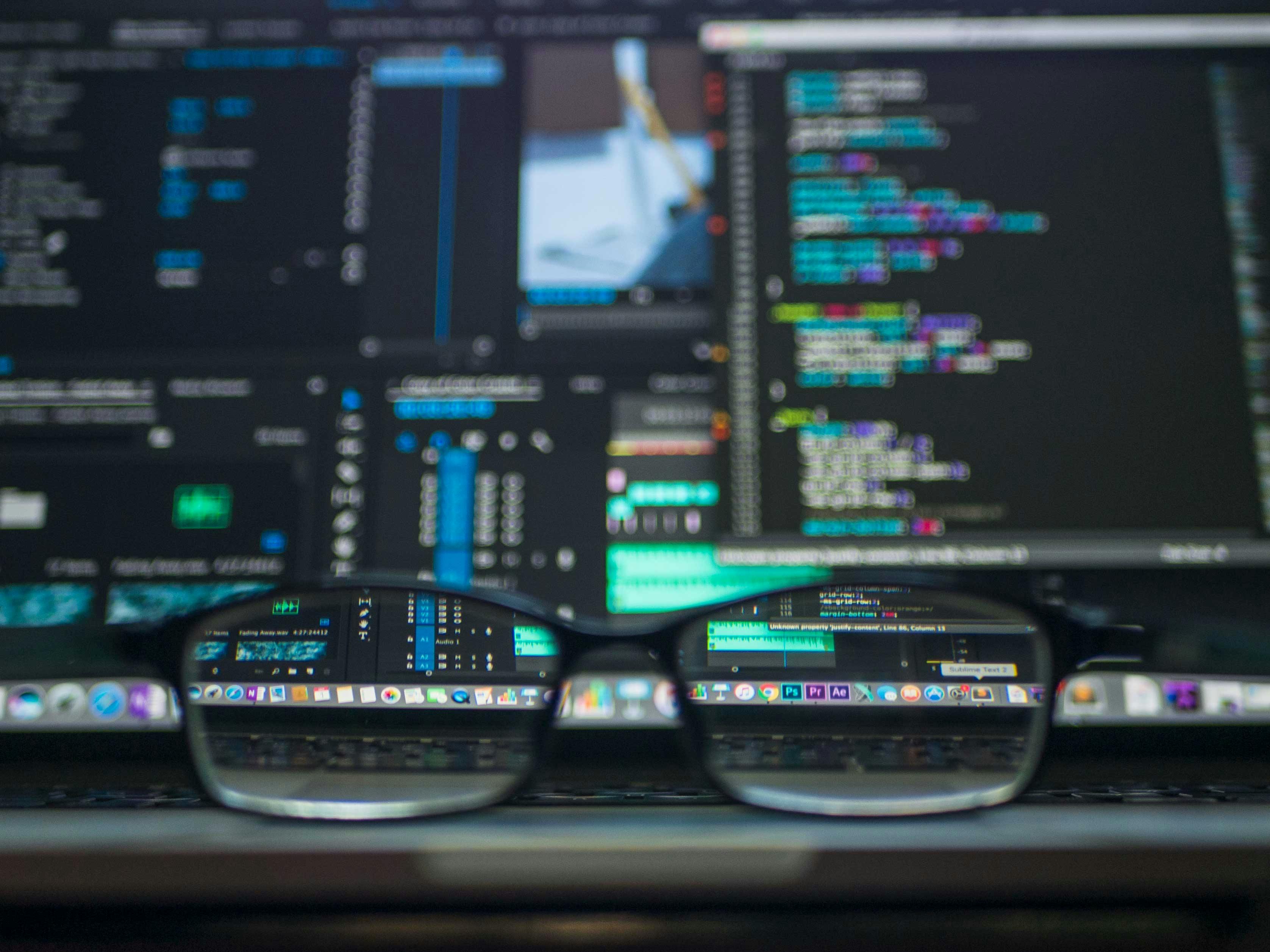 Glasses infront of a computer screen displaying lines of code.